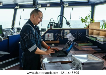 Marine navigational officer or technician is using laptop or notebook at sea. Job at sea
