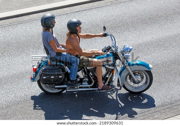 Marine Parade, Southend-on-Sea SS1 2EJ, UK \
August 10th 2022  A Harley Davidson Heritage Softail classic\
motorbike ridden by a shirtless man and female pillion passenger\
during hot summer\
heatwave.