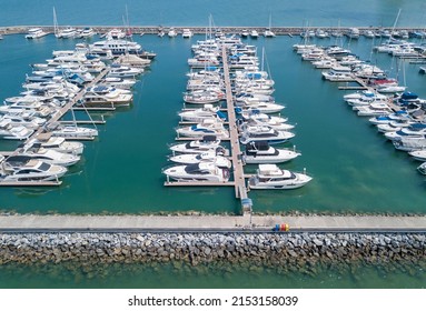 Marine Port For Yacht, Motorboat, Sailboat Parking Service Facility And Moorings For Luxury And Wealthy Millionaire In Aerial View With Many Ships Anchoring Alongside The Dock Bay