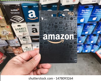 Marinette,WI/ U.S.A.-Aug1-2019:  Amazon gift card in a hand on gift cards background. Amazon is an American electronic commerce and cloud computing company based 