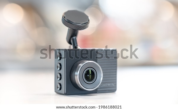 Marion, Iowa, USA - May 30, 2021: Side view of grey\
dash camera with buttons on light bokeh background, high quality\
video recorder device for vehicle, product from Garmin. Selective\
focus on lens.