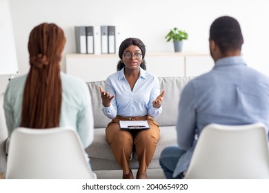 Marital Therapy Concept. Black Couple Sitting With Backs To Camera, Having Appointment With Psychologist At Office. Psychotherapist Helping Young Family Solve Their Marriage Problems