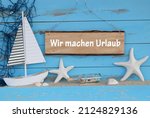 Maritime decoration with a sailing ship and shells.
German text wir machen Urlaub, translate We are on vacation.