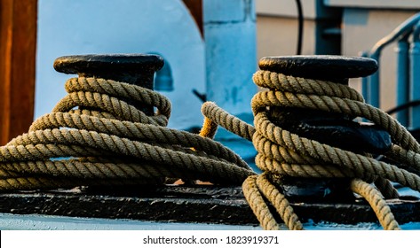 Maritime hemp rope moorings on a black cast iron bollard on the dock.