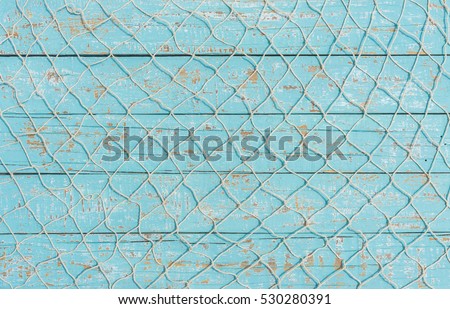 Maritime nautical fishing net texture on turquoise blue wood background, copy space. 