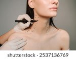 Mark up before Nefertiti lifting. Cosmetologist is drawing dotes before botulinum toxin injection in platysma of a woman. Improving neck by a professional. Female aesthetic cosmetology