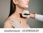 Mark up before Nefertiti lifting. Cosmetologist is drawing dotes before botulinum toxin injection in platysma of a woman. Improving neck by a professional. Female aesthetic cosmetology