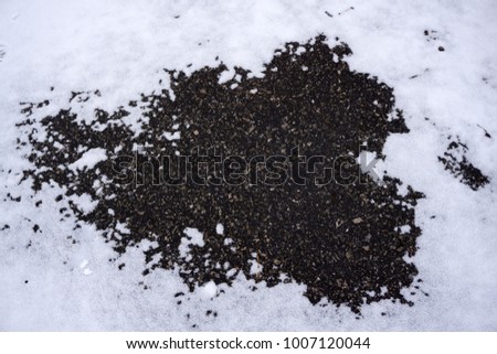 The mark left from a boot in a puddle with dirt and snow
