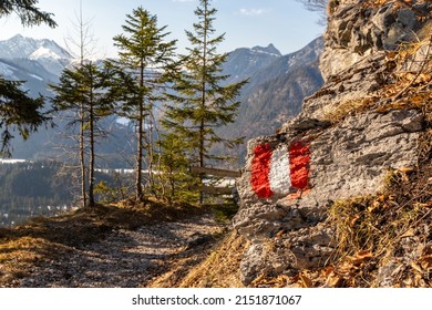 Marked alpine hiking trail in Austria, painted with the colors of an Austrian flag on a rock along the route. This painted rock is located near Pertisau and Achensee, in the Austrian Tyrol.