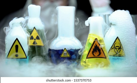 Marked dangerous liquids evaporating in flasks in front laboratory worker - Powered by Shutterstock