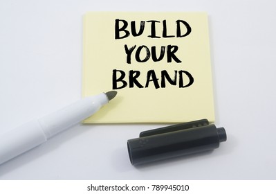 Marker Pens And Note Paper Written Build Your Brand Over White Background