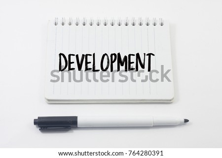 Marker pens and notebook with word development over white background