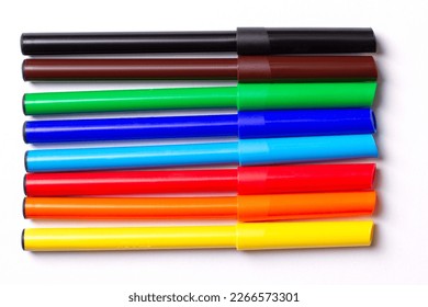 Marcadores de colores diferentes yacen en una fila. Sobre un fondo blanco.