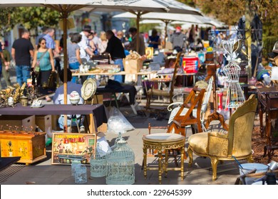 Market boot with objects beeing selled at the weekend flea market in the city center. Curious visitors in the background. - Shutterstock ID 229645399