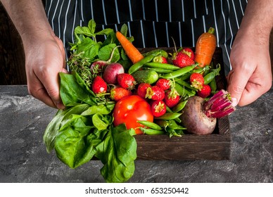 Market. Healthy vegan food. Fresh vegetables, berries, greens and fruits in wooden tray: spinach mint thyme strawberry carrots beets cucumbers radish green peas. On gray table. Copy space - Shutterstock ID 653250442