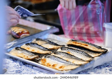 Market stall grilling freshly sliced mackerel bellies. Nutritious and delicious, customers purchasing.