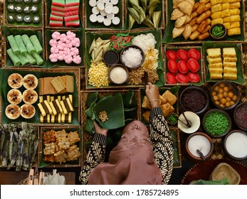Market stall of traditional Indonesian sweet and savory snacks. Here seen the lady seller scooping a snack called Tiwul from the tray.