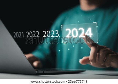 Market trend for 2024. Businessman touching virtual number 2024 for Merry christmas and happy new year concept. End of the old year and start of new business in 2024.