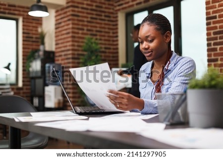 Marketing agency office person having management documentation while sitting at desk. Young confident business woman reviewing accounting annual results and financial plan.