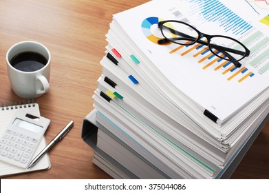 Marketing Data Analysis. Wooden Table.
Wooden Office Desk With Pile Of Documents, Calculator And Coffee Mug.
