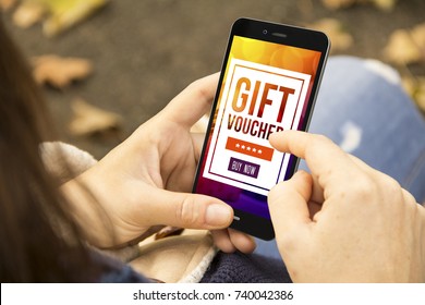 Marketing Digital Concept: Woman Holding A 3d Generated Smartphone With Gift Voucher On The Screen. Graphics On Screen Are Made Up.