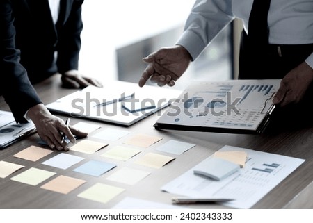 The marketing executive team is using all the information they have collected and transcribing it onto sticky color notes and putting it on the meeting table so they can come up with the best ideas an
