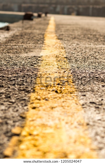 marking\
separating yellow stripe road,  label extending far close-up.\
Perspective vertical photo yellow strip\
road