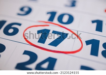 Marking the seventeenth 17 day of a month in the calendar with a red marker. Note of the calendar, significant date. Signing the day on the calendar. Reminder mark on the eighteenth 18 day of month. 