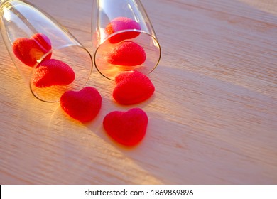 Marmalade Red Hearts And Two Glasses Of Champange On The Wooden Table Close-up. Abstract Romantic Background. Selective Focus.