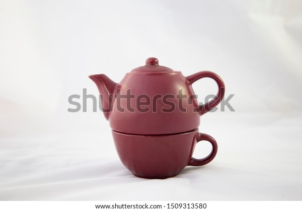 Maroon ceramic teapot on white background.\
Individual view. Trim. It is divided into two parts because it is\
an individual teapot that has the glass for tea at the bottom. Two\
handles are seen