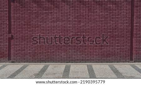 Maroon colored brick wall background front view. Large brickwall at city street.