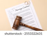 Marriage contract, gavel and golden rings on beige background, top view