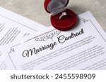 Marriage contract and ring with gemstone on grey table
