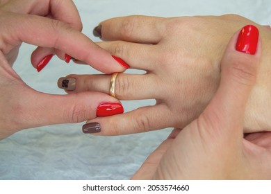 Marriage equality. Close up - hands of a lesbian couple with a wedding ring. A girl with a red manicure puts a ring on another girl's finger. same-sex matchmaker. lgbt