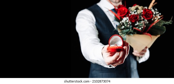 Marriage proposal. Diamond engagement ring, red roses bouquet in young happy man hands. Diamond ring propose in Valentine Day