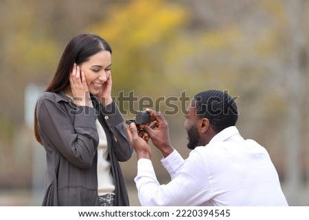 Marriage proposal of a happy interracial couple in a park