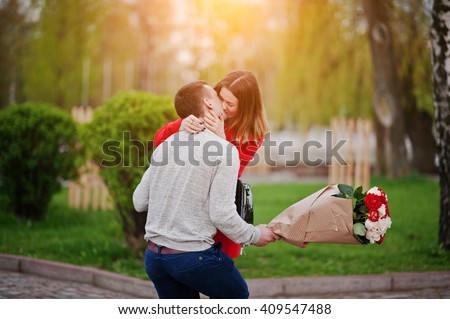 Marriage proposal. Kissed girl and boyfriend with bouquet of flowers