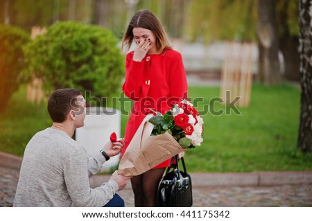 Marriage proposal. Man with boquet of flowers kneeling and give engagement ring for his girlfriend