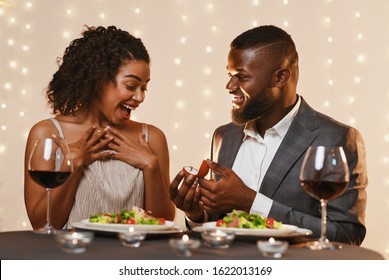 Marriage Proposal At Valentine's Day. Black man making marriage proposal to his surprised beautiful woman while having dinner at restaurant