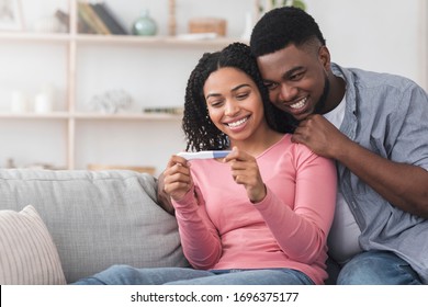 Married black couple happy with positive results of pregnancy test, loving man hugging his wife, copy space