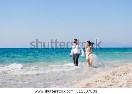 A married couple, bride and groom, together in sunshine on a beautiful tropical beach
