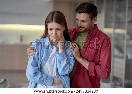 Married couple calmly solving problems in relationship. Peaceful guy husband smiles, trying to instill confidence in frustrated disappointed girl wife, calm down with presence, support, improve mood.