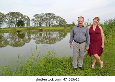 The married couple costs on the bank of a pond in summer day