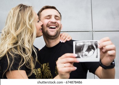 A Married Couple Is Happy With Pregnancy, An Ultrasound Picture Of A Baby In The Hand. Artificial Insemination.