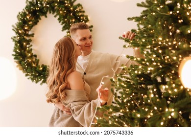 A married couple in love are preparing together for the Christmas holiday during the New Year holidays in a decorated house. Two people decorate the Christmas tree in anticipation. Selective focus 