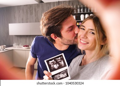 A married couple in love videocall their parents using a tablet, to announce the birth of their son showing the ultrasound. Concept of: family, birth, life, love - Powered by Shutterstock