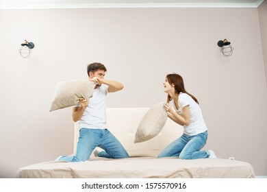 Married Couple Man And Woman Fight Pillows On The Bed