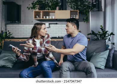 Married Couple, Man And Woman, Sitting On The Couch At Home And Arguing Over The Phone, Jealousy