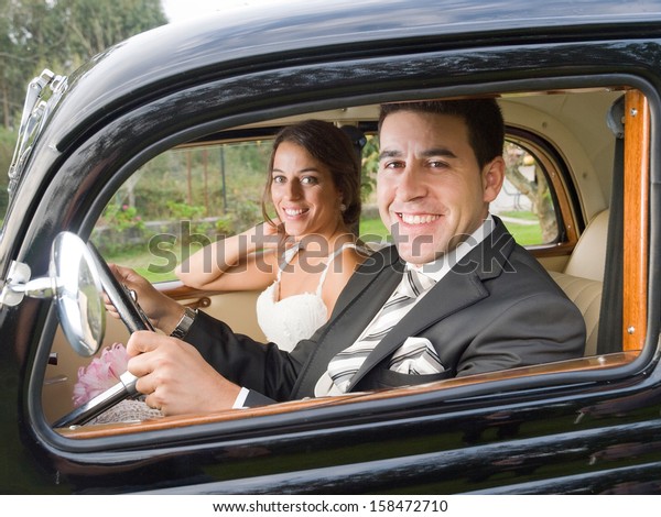 Married\
couple in a old car. They are looking at\
camera.