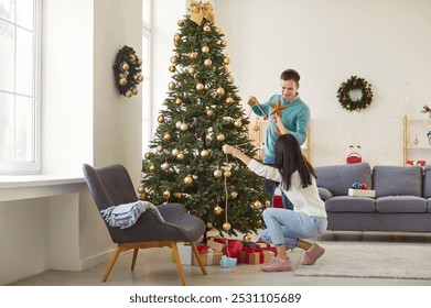 Married couple preparing for Christmas or New Year by decorating a tree at home. They enjoy the festive anticipation and the joy of the holiday season while creating a warm and cheerful atmosphere. - Powered by Shutterstock